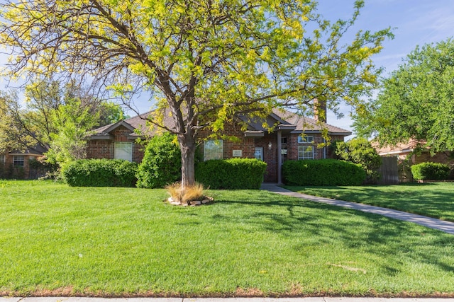 view of front of home featuring brick siding, fence, and a front yard