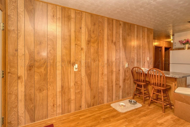 1909 N Wells St, Pampa, TX 79065 - dining room featuring wood finished floors, wood walls, a dry bar, and a textured ceiling
