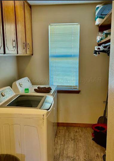 washroom with washer and clothes dryer, cabinets, and light hardwood / wood-style floors