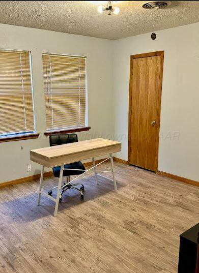 home office with hardwood / wood-style floors and a textured ceiling