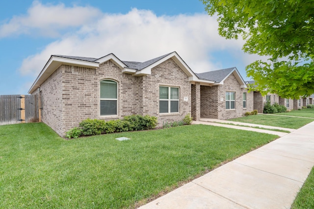 ranch-style house with brick siding, a front lawn, and fence