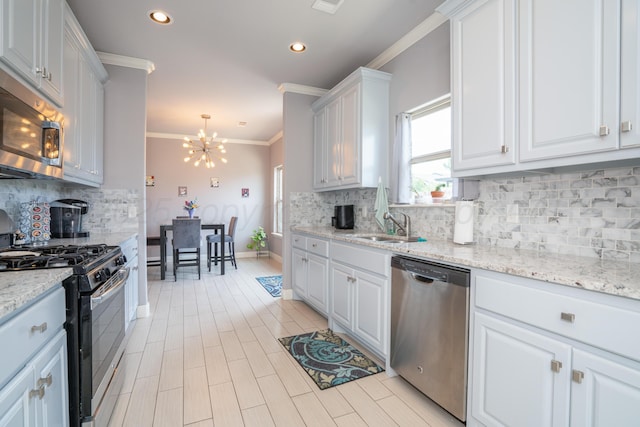 kitchen featuring a notable chandelier, appliances with stainless steel finishes, a sink, white cabinetry, and ornamental molding