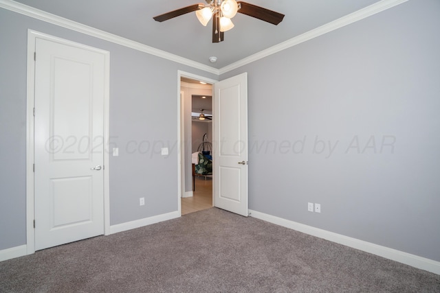 unfurnished bedroom with baseboards, carpet flooring, crown molding, and a ceiling fan