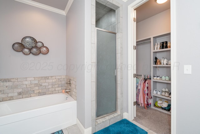full bathroom with ornamental molding, a bath, a stall shower, and a walk in closet