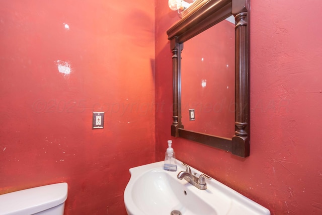 bathroom featuring a textured wall, a sink, and toilet