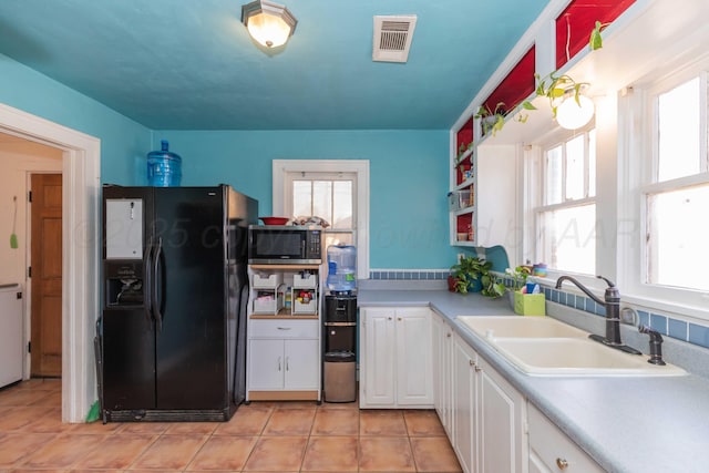 kitchen featuring a sink, visible vents, white cabinetry, black refrigerator with ice dispenser, and stainless steel microwave