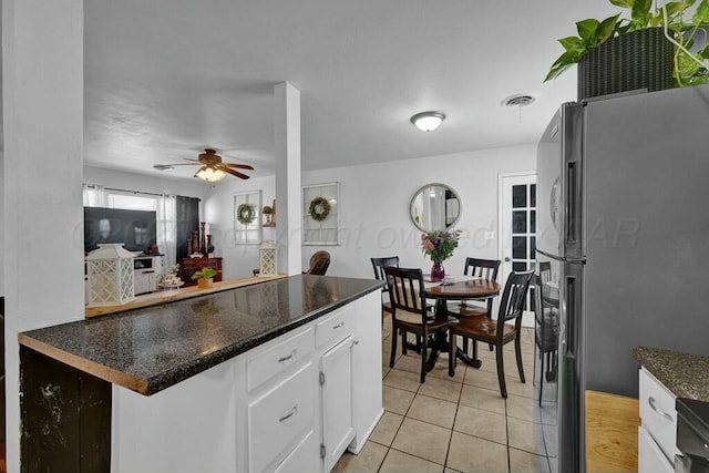 kitchen featuring visible vents, a ceiling fan, freestanding refrigerator, white cabinetry, and light tile patterned flooring