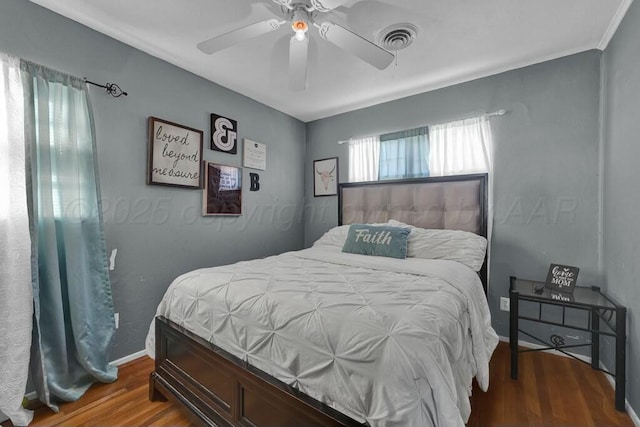 bedroom featuring visible vents, ceiling fan, baseboards, and wood finished floors