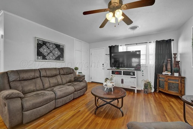 living room with a ceiling fan, visible vents, and wood finished floors