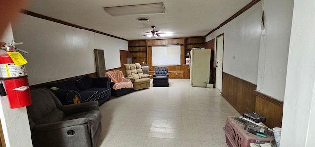 living room with wood walls, ceiling fan, and ornamental molding