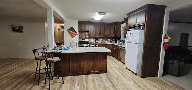 kitchen featuring stainless steel appliances, dark brown cabinetry, sink, tasteful backsplash, and light wood-type flooring