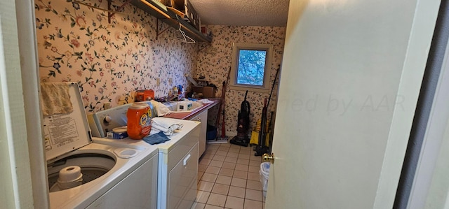 clothes washing area with washer and dryer, a textured ceiling, and light tile patterned floors