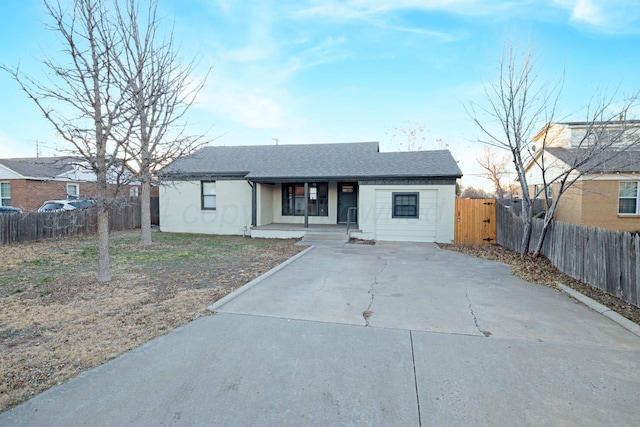 ranch-style house featuring a porch, fence, and a shingled roof