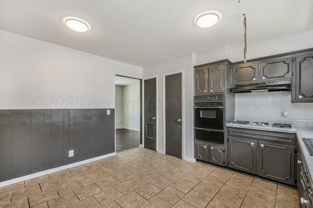 2902 Pryor St, Amarillo, TX 79103 - kitchen featuring black oven, a warming drawer, under cabinet range hood, white gas stovetop, and light countertops