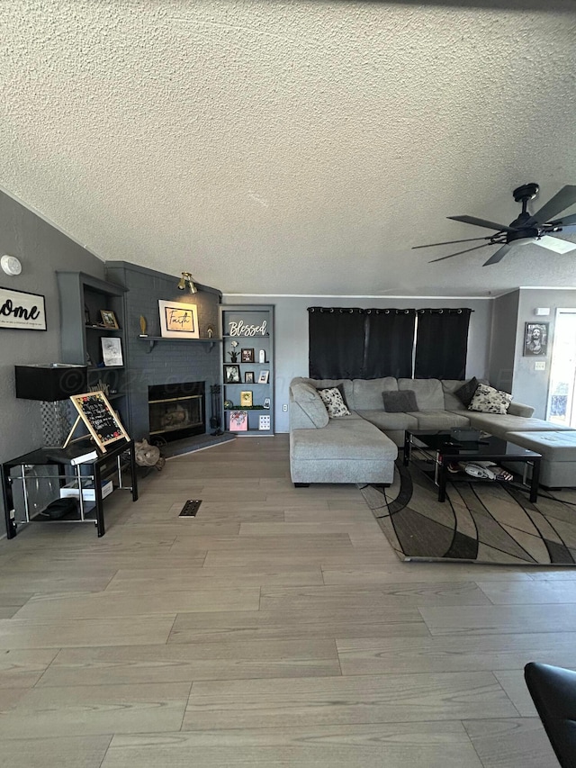 712 Groom Ave, Panhandle, TX 79068 - living area featuring wood finished floors, a textured ceiling, a ceiling fan, and a brick fireplace