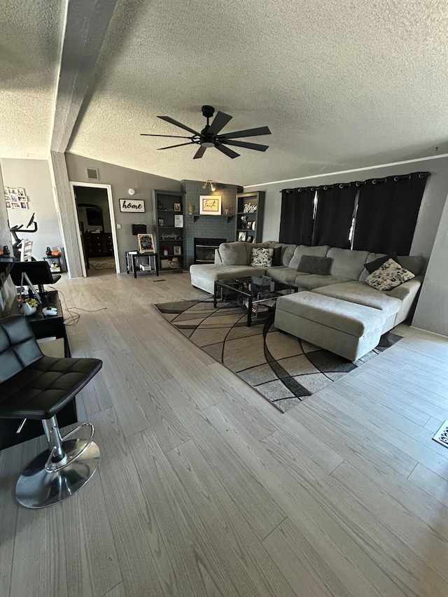 712 Groom Ave, Panhandle, TX 79068 - living area featuring ceiling fan, wood finished floors, a textured ceiling, and a large fireplace