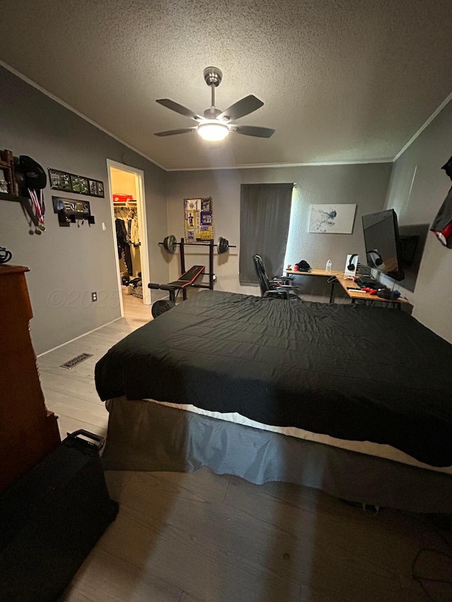 712 Groom Ave, Panhandle, TX 79068 - bedroom featuring crown molding, a textured ceiling, a walk in closet, a ceiling fan, and wood finished floors