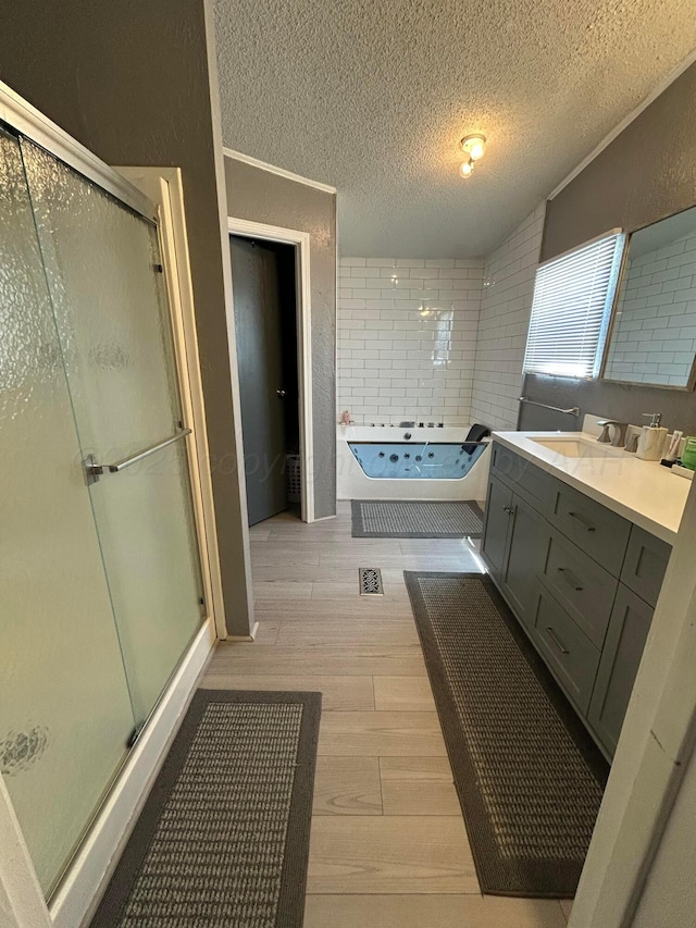 712 Groom Ave, Panhandle, TX 79068 - bathroom featuring a textured ceiling, vanity, a shower stall, wood finished floors, and a garden tub
