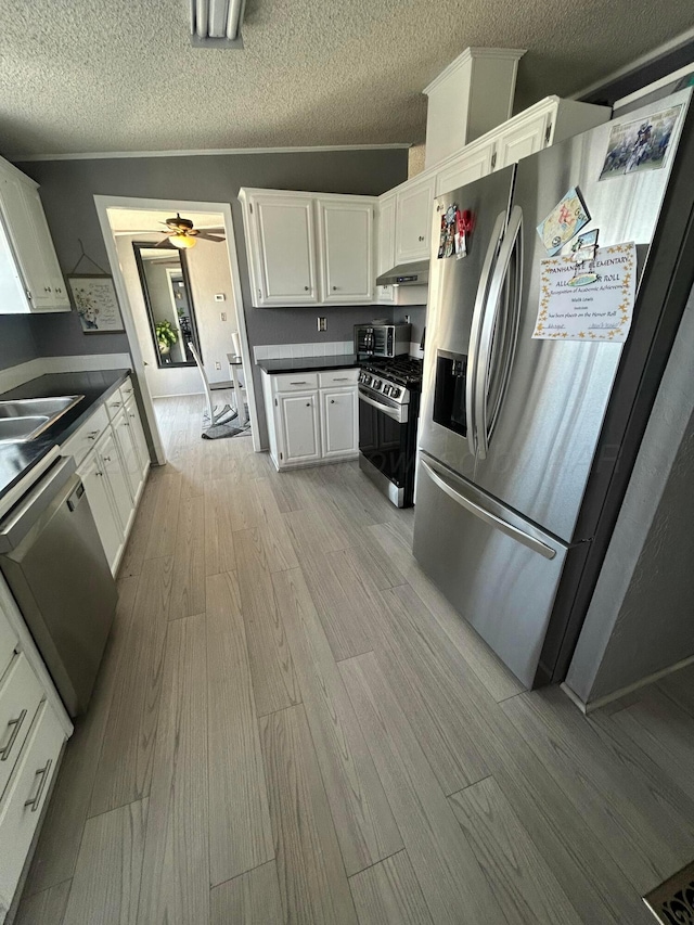 712 Groom Ave, Panhandle, TX 79068 - kitchen featuring appliances with stainless steel finishes, dark countertops, wood finished floors, white cabinetry, and a textured ceiling