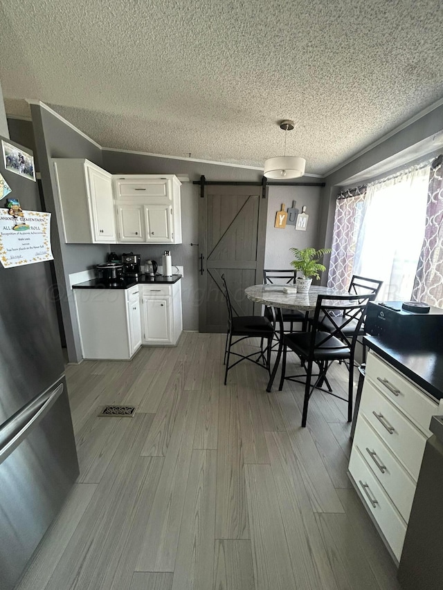 712 Groom Ave, Panhandle, TX 79068 - kitchen with freestanding refrigerator, a barn door, a textured ceiling, wood finished floors, and white cabinetry