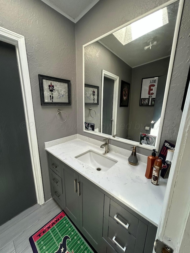712 Groom Ave, Panhandle, TX 79068 - bathroom featuring vanity, a skylight, wood finished floors, a textured wall, and ornamental molding
