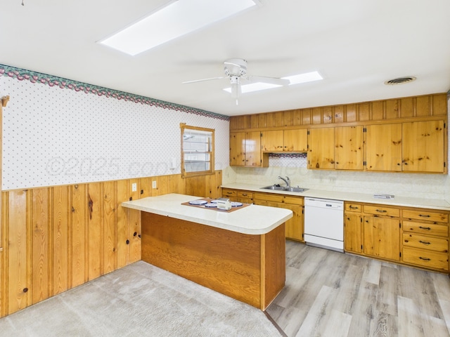 502 Spruce Ave, Dumas, TX 79029 - kitchen with dishwasher, a sink, a peninsula, light countertops, and brown cabinetry