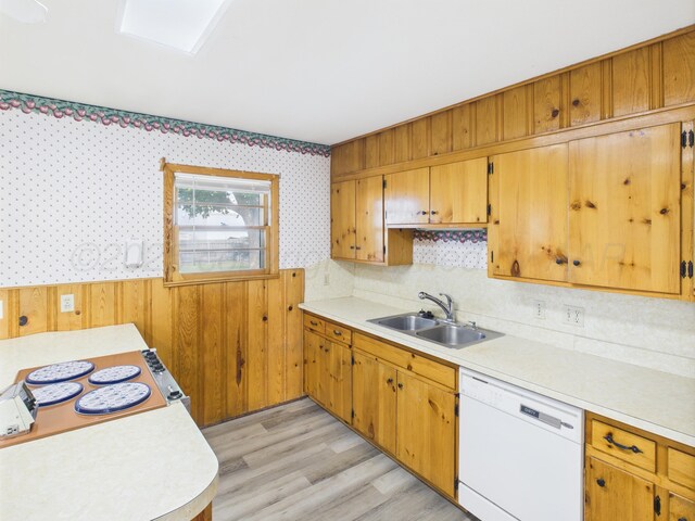 502 Spruce Ave, Dumas, TX 79029 - kitchen with white dishwasher, a sink, light countertops, a wainscoted wall, and wooden walls