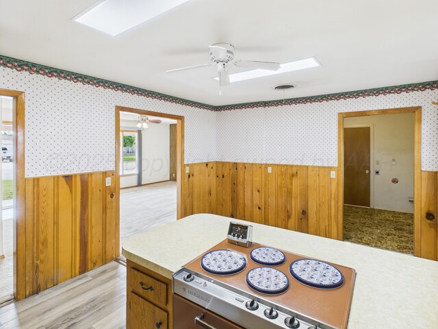 502 Spruce Ave, Dumas, TX 79029 - kitchen with wainscoting, wallpapered walls, light countertops, ceiling fan, and light wood-type flooring