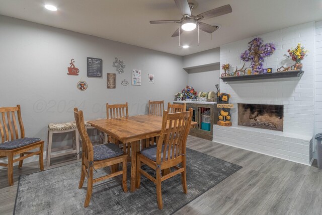 dining area with hardwood / wood-style flooring, ceiling fan, and a fireplace