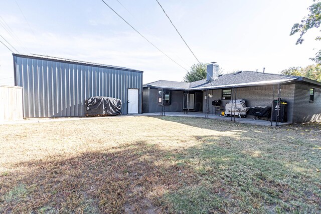 rear view of property featuring a lawn and a patio