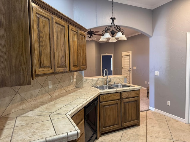 kitchen with tile countertops, dishwasher, crown molding, and a sink