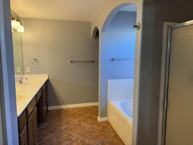 bathroom with double vanity, baseboards, tile patterned floors, a sink, and a bath