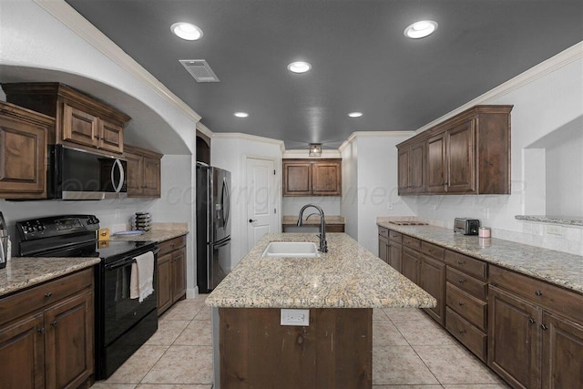 kitchen featuring stainless steel microwave, a sink, freestanding refrigerator, a kitchen island with sink, and electric range