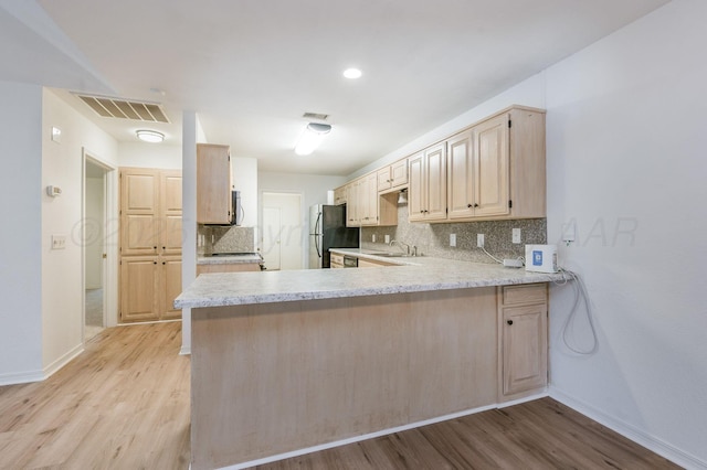 6011 Belpree Rd, Amarillo, TX 79106 - kitchen with light brown cabinetry, light wood-type flooring, appliances with stainless steel finishes, and decorative backsplash