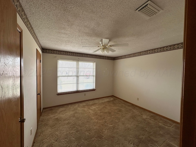 spare room with a textured ceiling, visible vents, baseboards, ceiling fan, and carpet floors