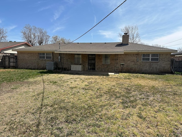 rear view of property featuring a lawn, central air condition unit, fence, and a chimney