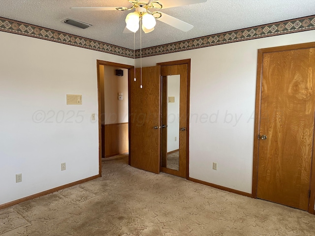 unfurnished bedroom with light carpet, a textured ceiling, baseboards, and visible vents