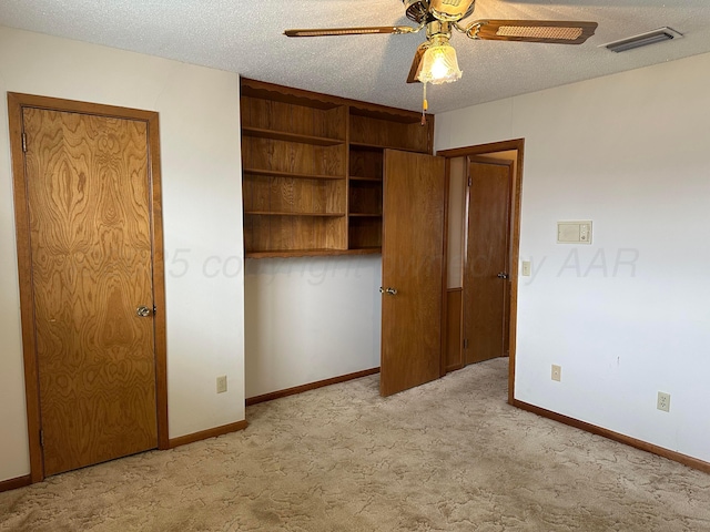 unfurnished bedroom with baseboards, a textured ceiling, ceiling fan, visible vents, and light carpet