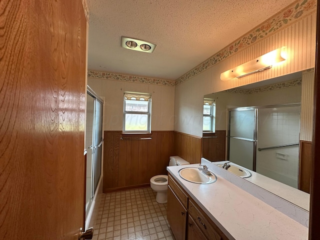 bathroom featuring an enclosed shower, a wainscoted wall, a textured ceiling, and toilet