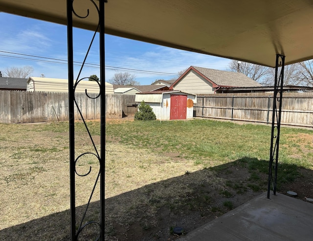 view of yard with a storage unit, a fenced backyard, and an outbuilding