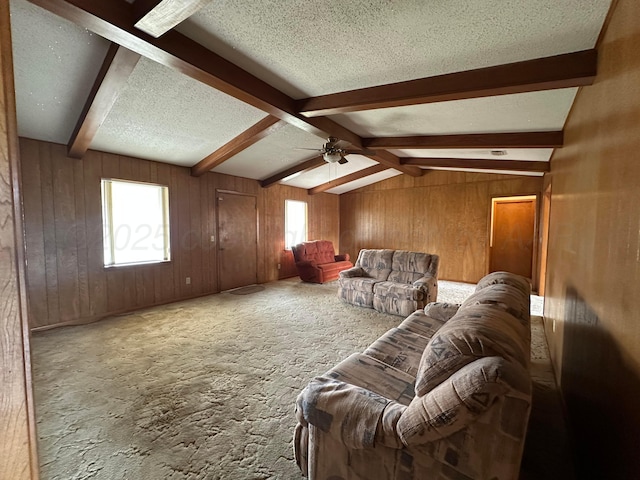 living room with plenty of natural light, wood walls, vaulted ceiling with beams, and a textured ceiling
