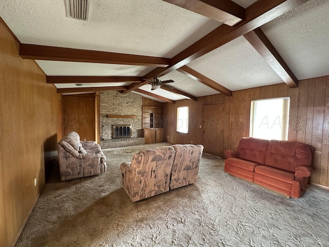 living area with vaulted ceiling with beams, a fireplace, wood walls, and a textured ceiling