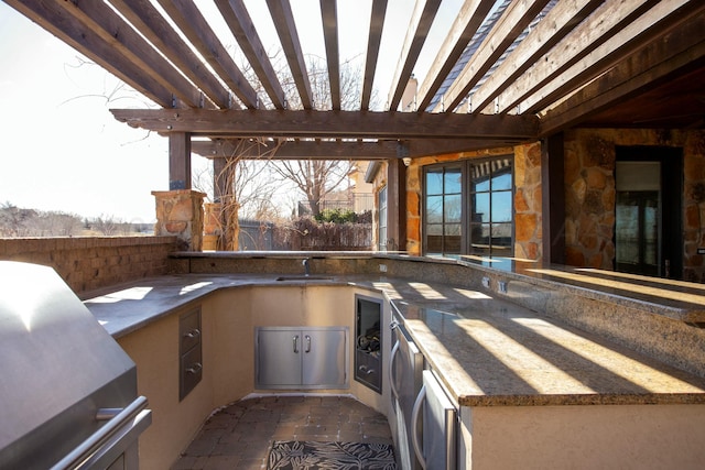 view of patio featuring an outdoor kitchen, sink, and a pergola