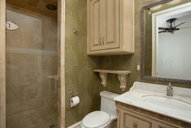 bathroom with a shower with door, vanity, ceiling fan, and toilet