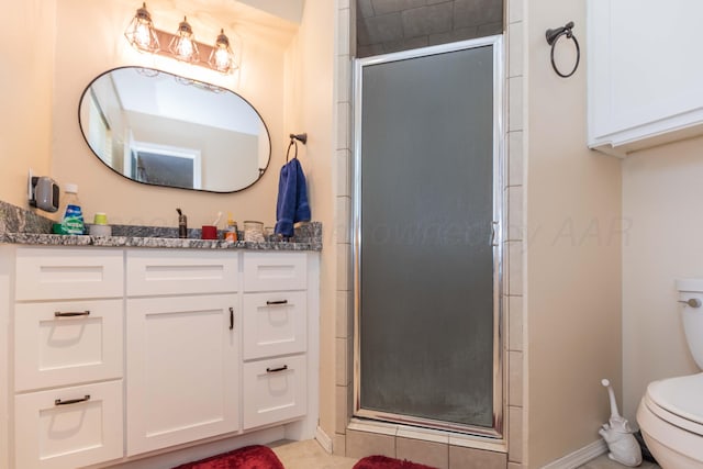 bathroom with a shower stall, tile patterned flooring, toilet, vanity, and baseboards