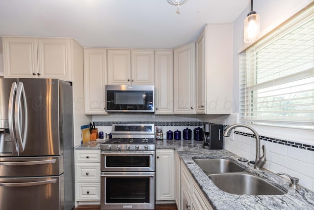 kitchen with tasteful backsplash, light stone countertops, stainless steel appliances, and a sink