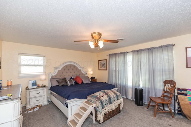 bedroom with ceiling fan, visible vents, a textured ceiling, and light colored carpet