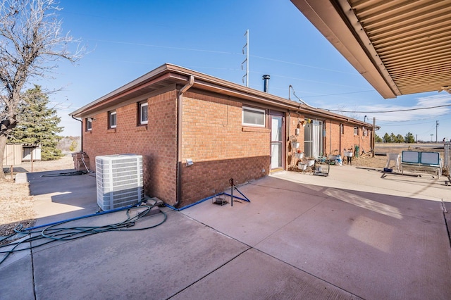 back of house featuring a patio area, brick siding, and central AC unit