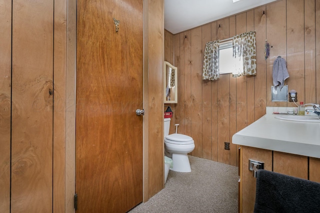 bathroom with wood walls, vanity, and toilet