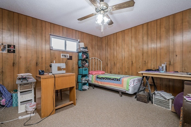 carpeted bedroom with ceiling fan, wooden walls, and a textured ceiling